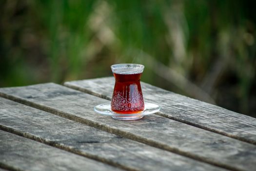 Elegant Turkish tea served in ornate glass with outdoor wooden table setting.