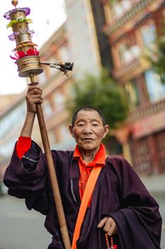 Portrait of an elderly Tibetan man with a prayer wheel in Garzê, Sichuan.