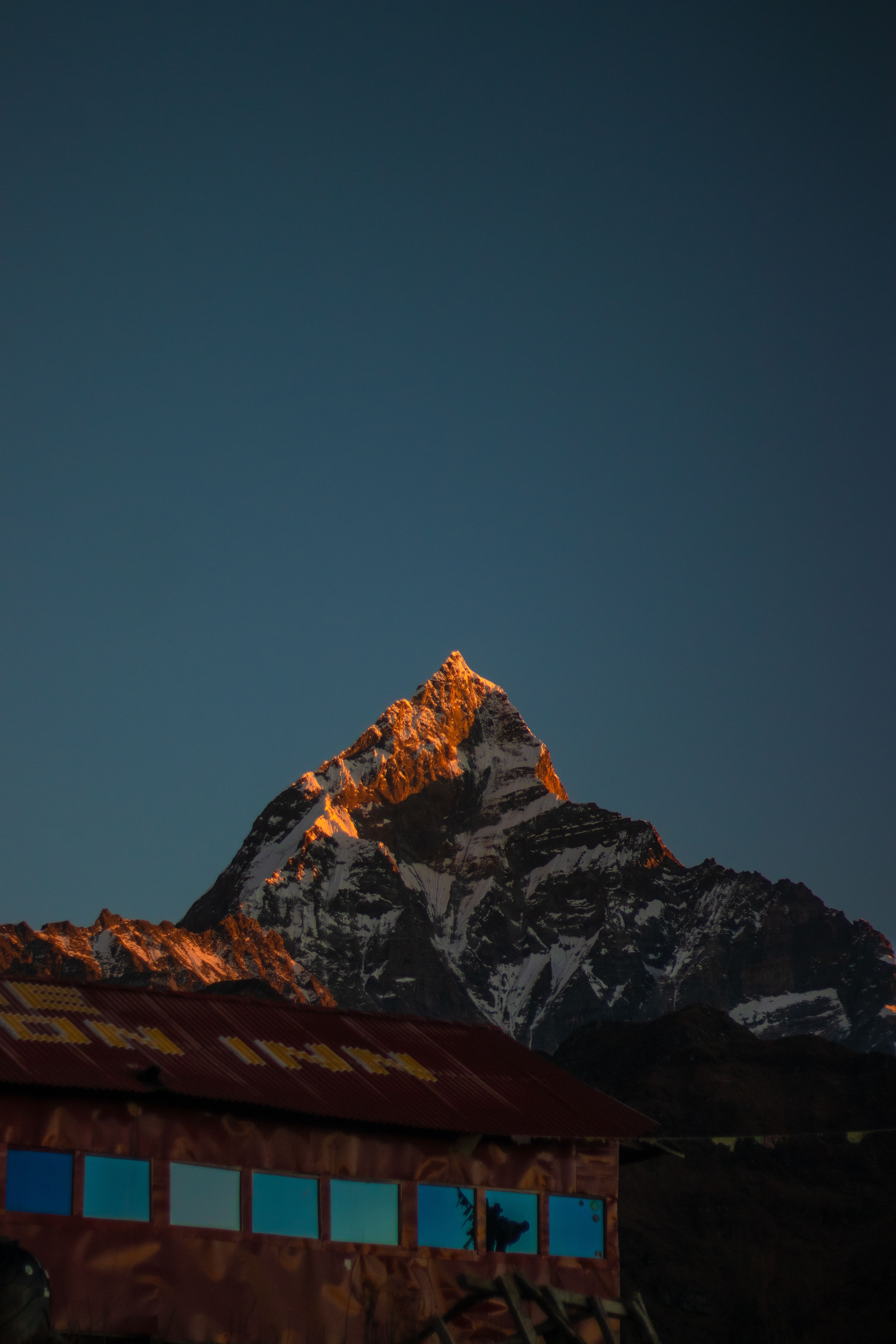 Golden sunlight touches the peak of Machapuchare at sunset, a serene Himalayan landscape.
