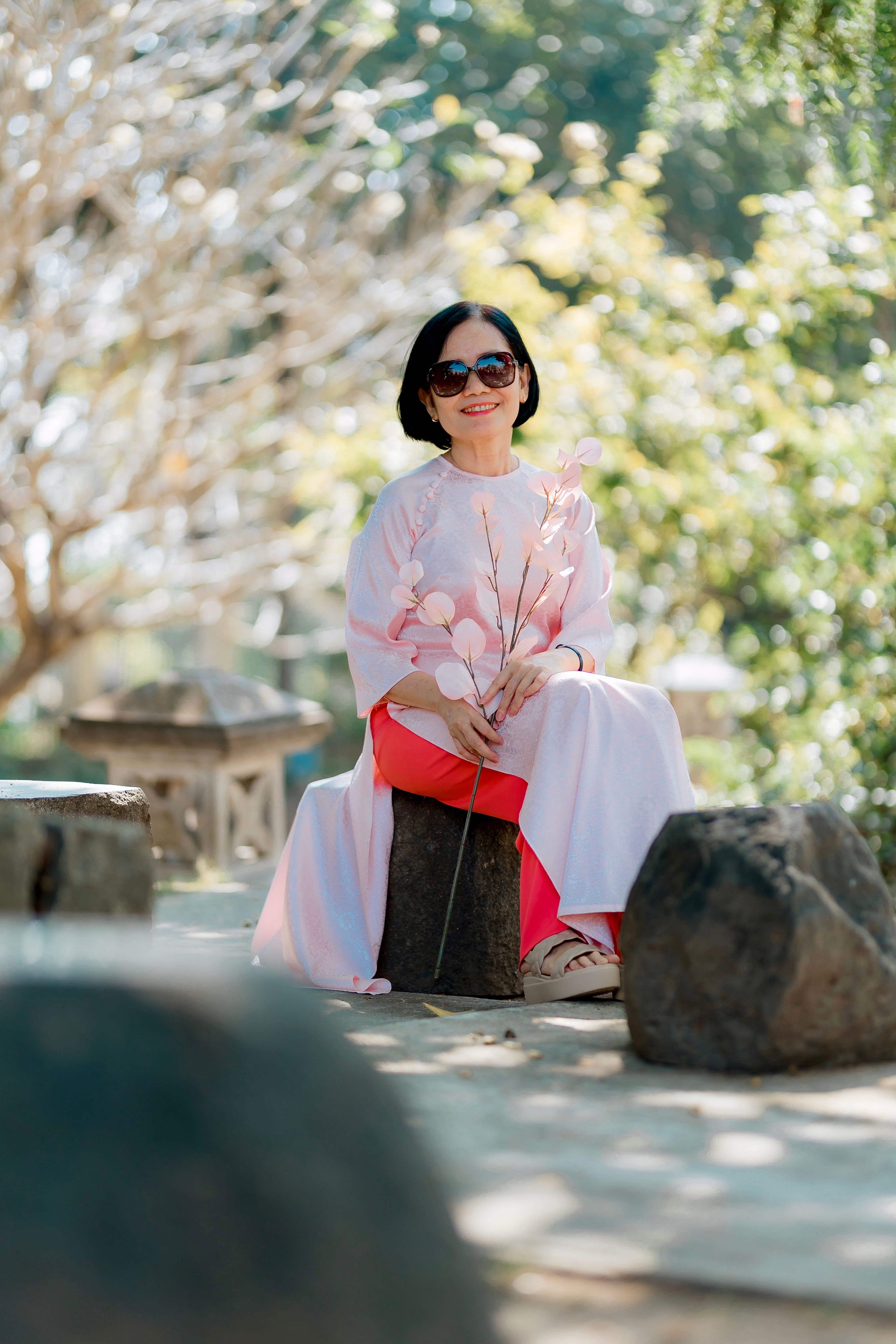 Elegant Woman Relaxing in Sunny Park with Flowers · Free Stock Photo