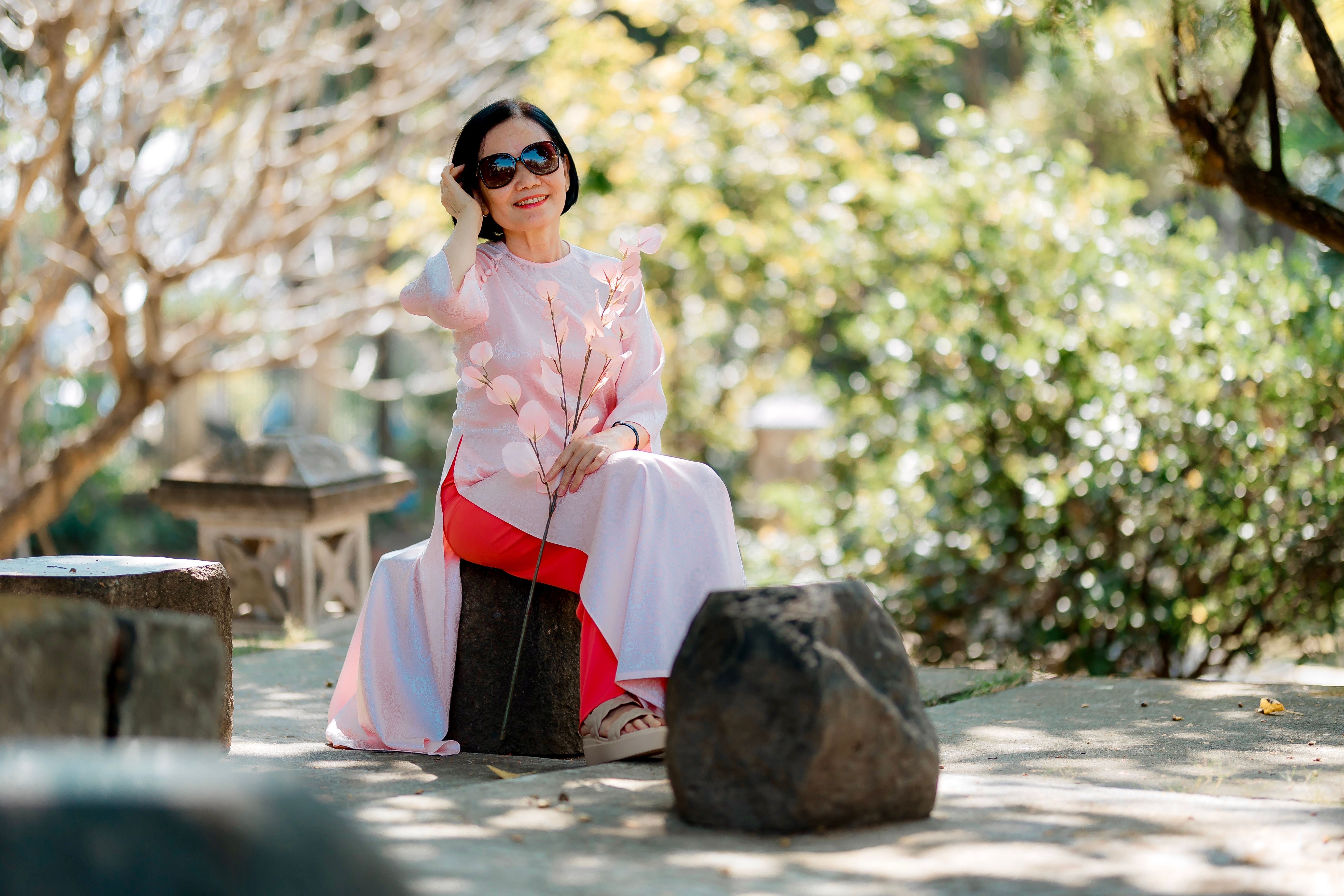 Elegant Woman in Pink Dress Sitting Outdoors · Free Stock Photo