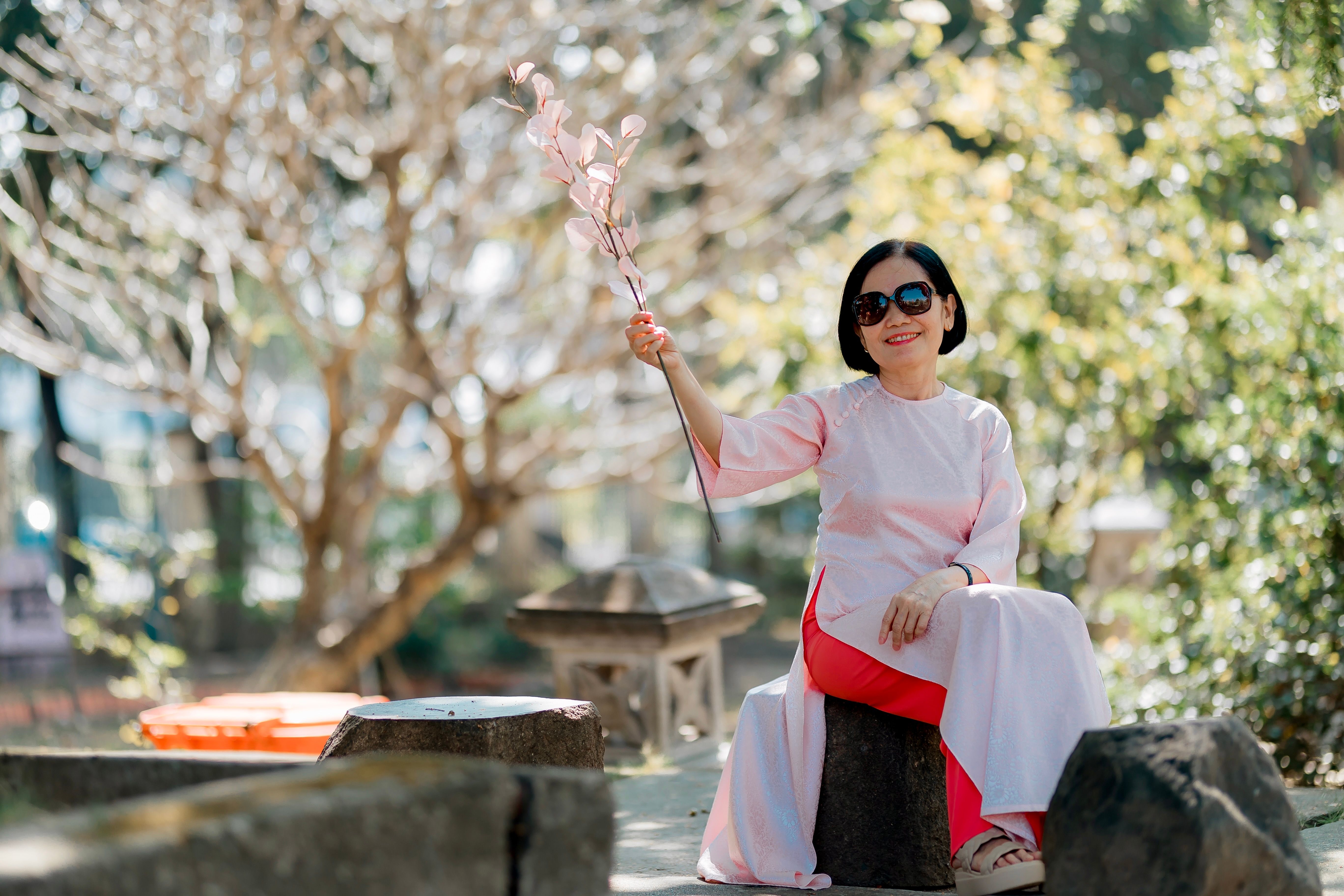 Elegant Woman in Traditional Dress Holding Flowers · Free Stock Photo