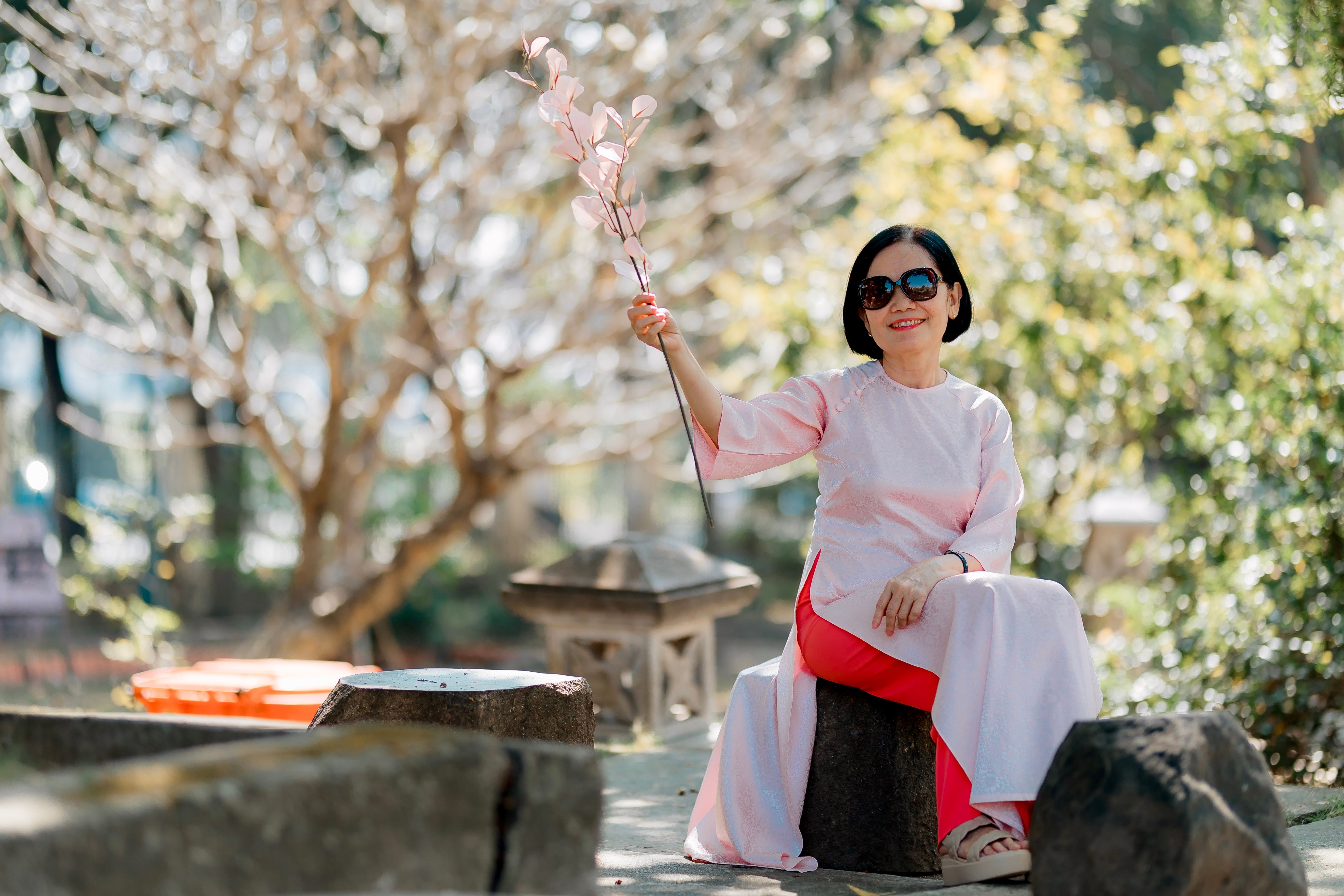Elegant Woman in Pink Dress Holding Flowers Outdoors · Free Stock Photo
