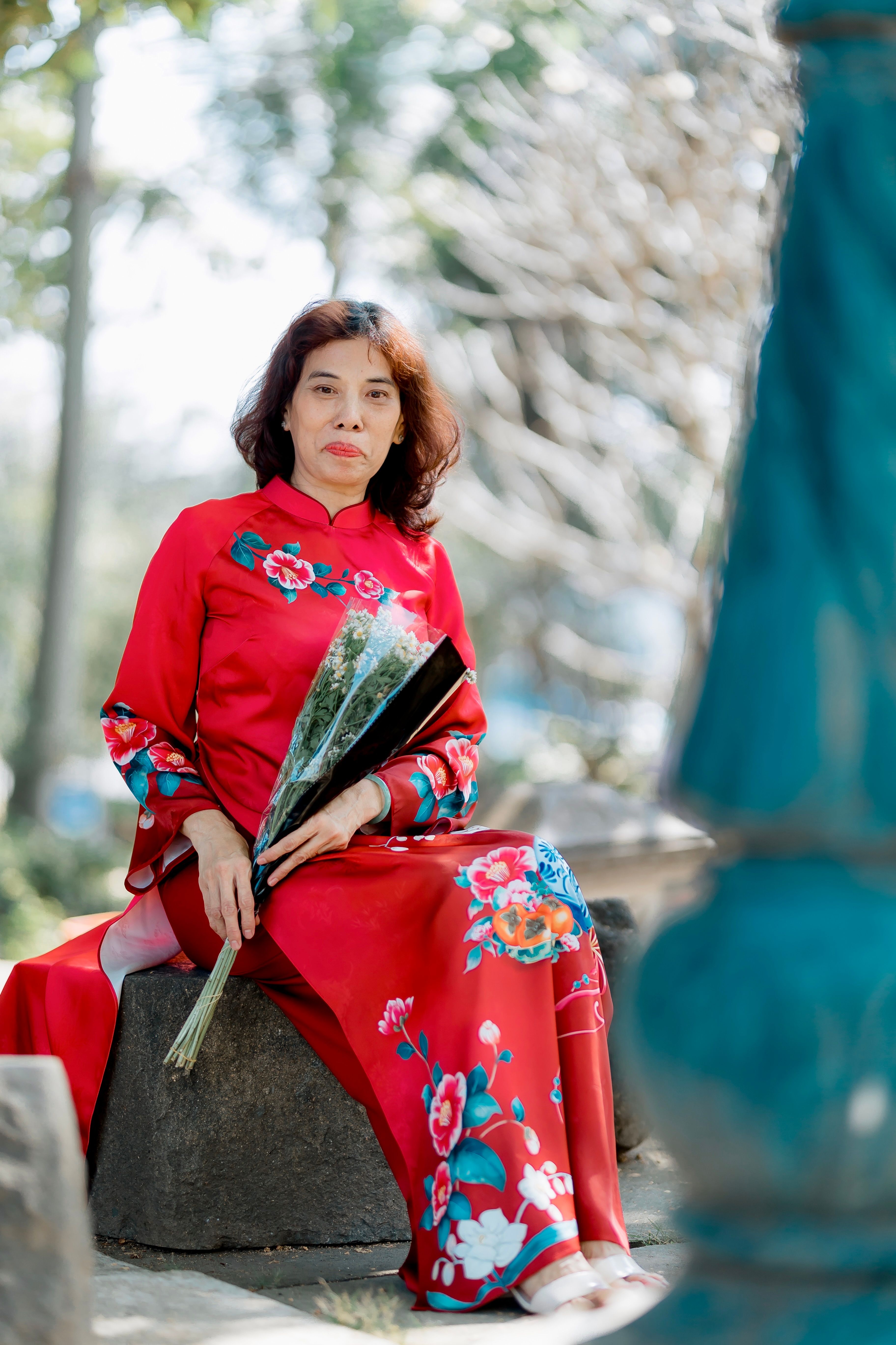 Elegant Woman in Red Dress Holding Flowers Outdoors · Free Stock Photo