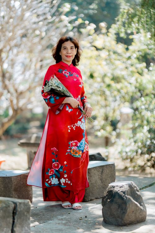 Woman in Red Traditional Dress Holding Flowers Outdoors · Free Stock Photo