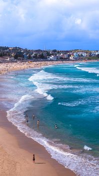 Vibrant scene of Bondi Beach, Sydney, showcasing clear blue waves and bustling shoreline.