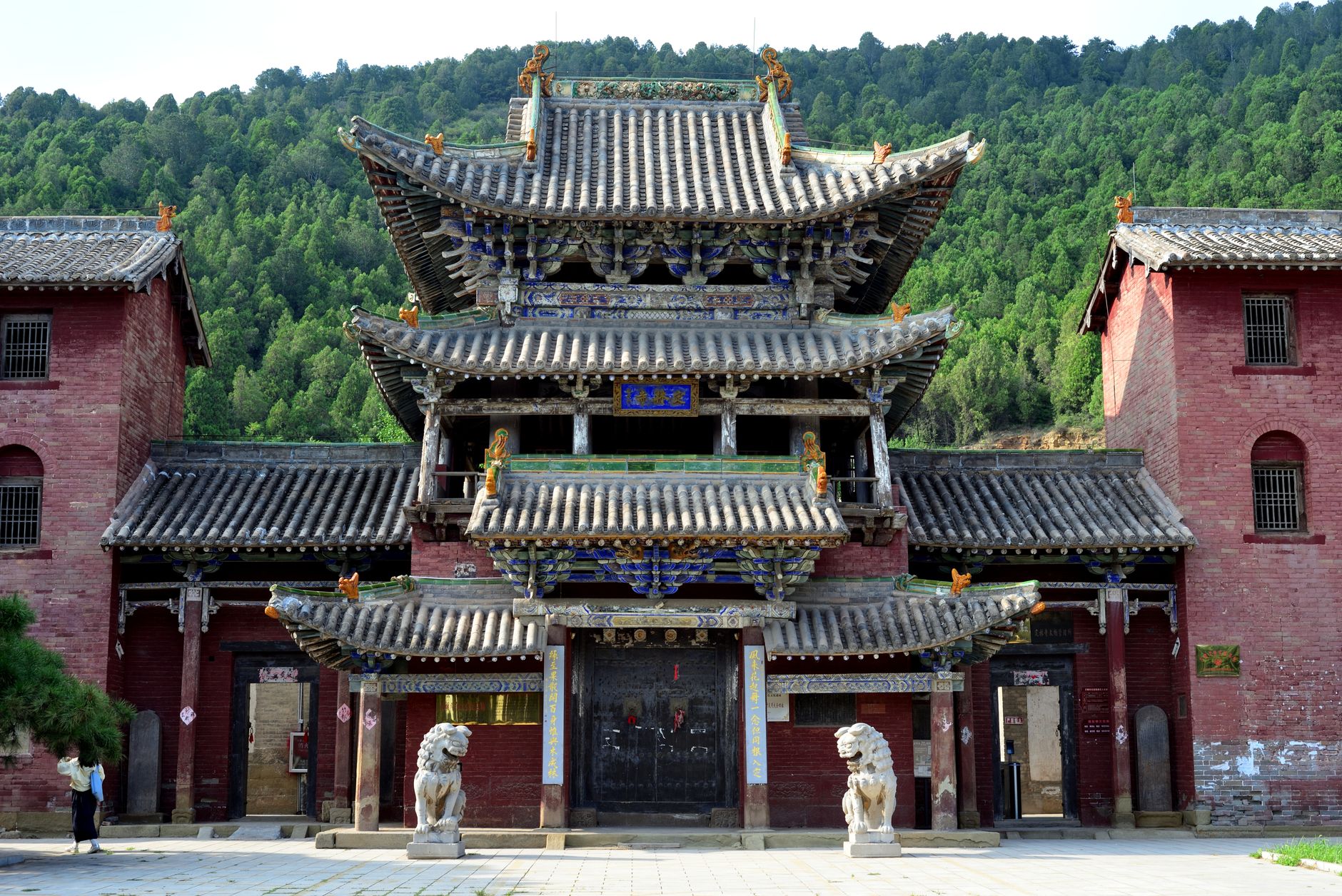 Intricate Chinese temple with ornate architecture set against lush forest backdrop.
