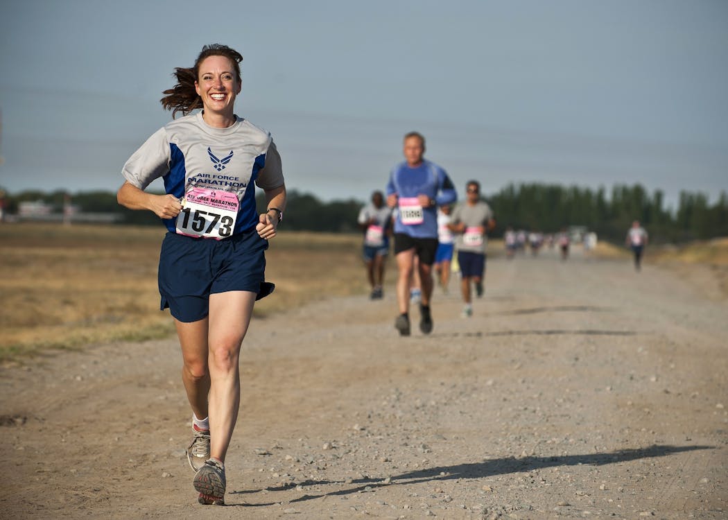 Woman in Gray Crew Neck Shirt Running on Brown Soil during Daytime