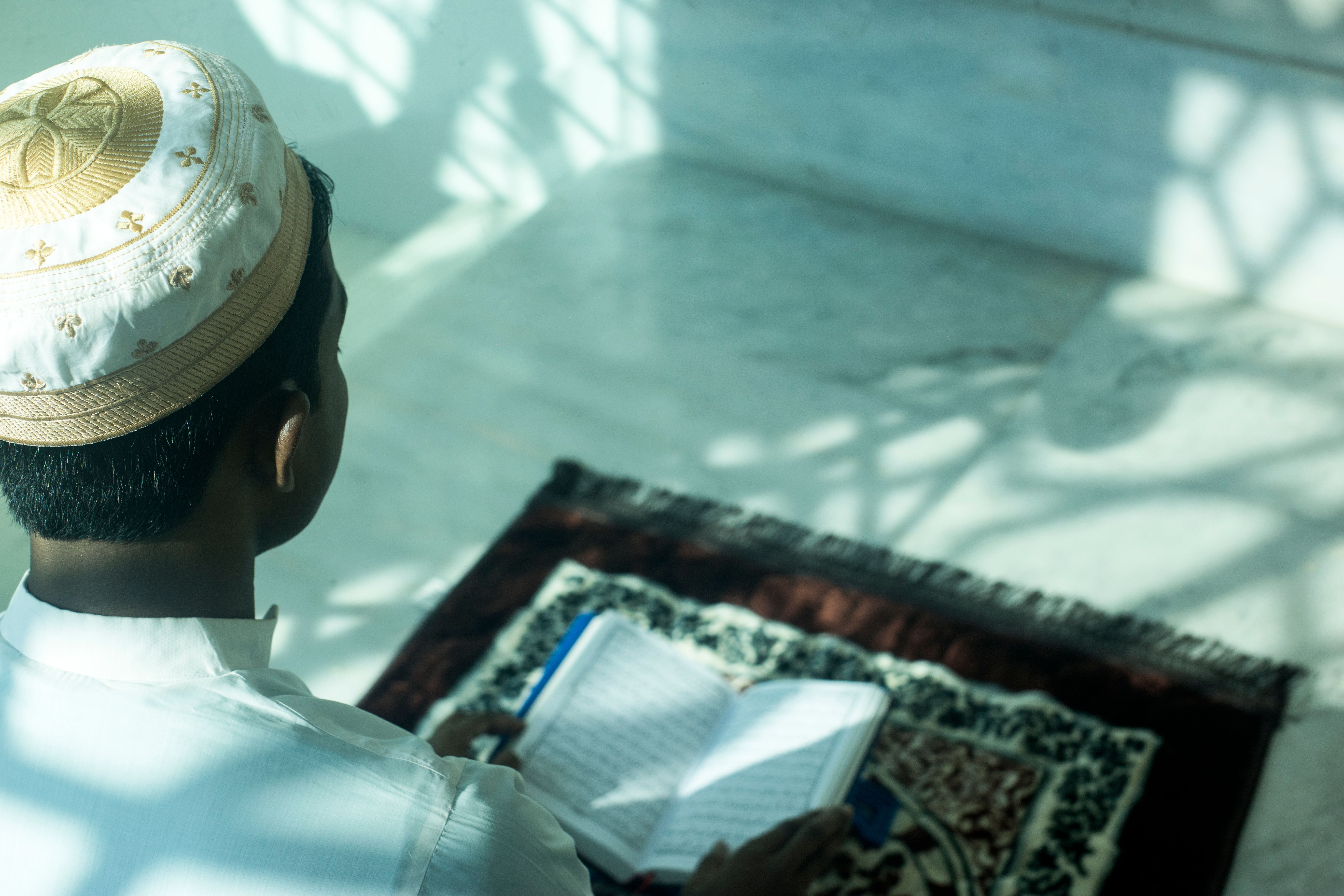 student checking hostel reviews on a laptop with a prayer mat in the background