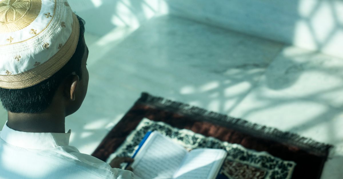 student checking hostel reviews on a laptop with a prayer mat in the background