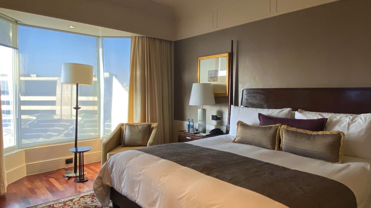Modern hotel room with a made bed and a large window overlooking the city