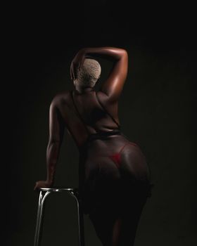 Elegant low-light portrait of woman in lingerie sitting on stool with back turned.