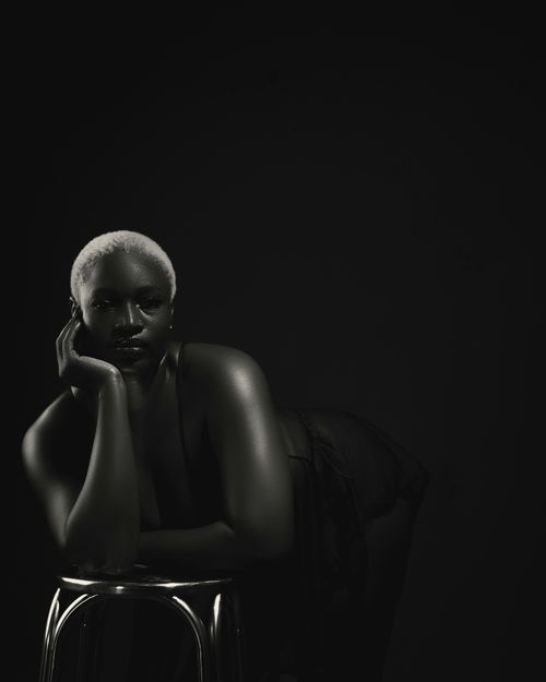 Free Striking black and white portrait of a woman resting on a stool in a dramatic pose. Stock Photo