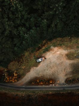 Aerial photo of a campervan parked in a secluded area surrounded by lush autumn forest in the UK.