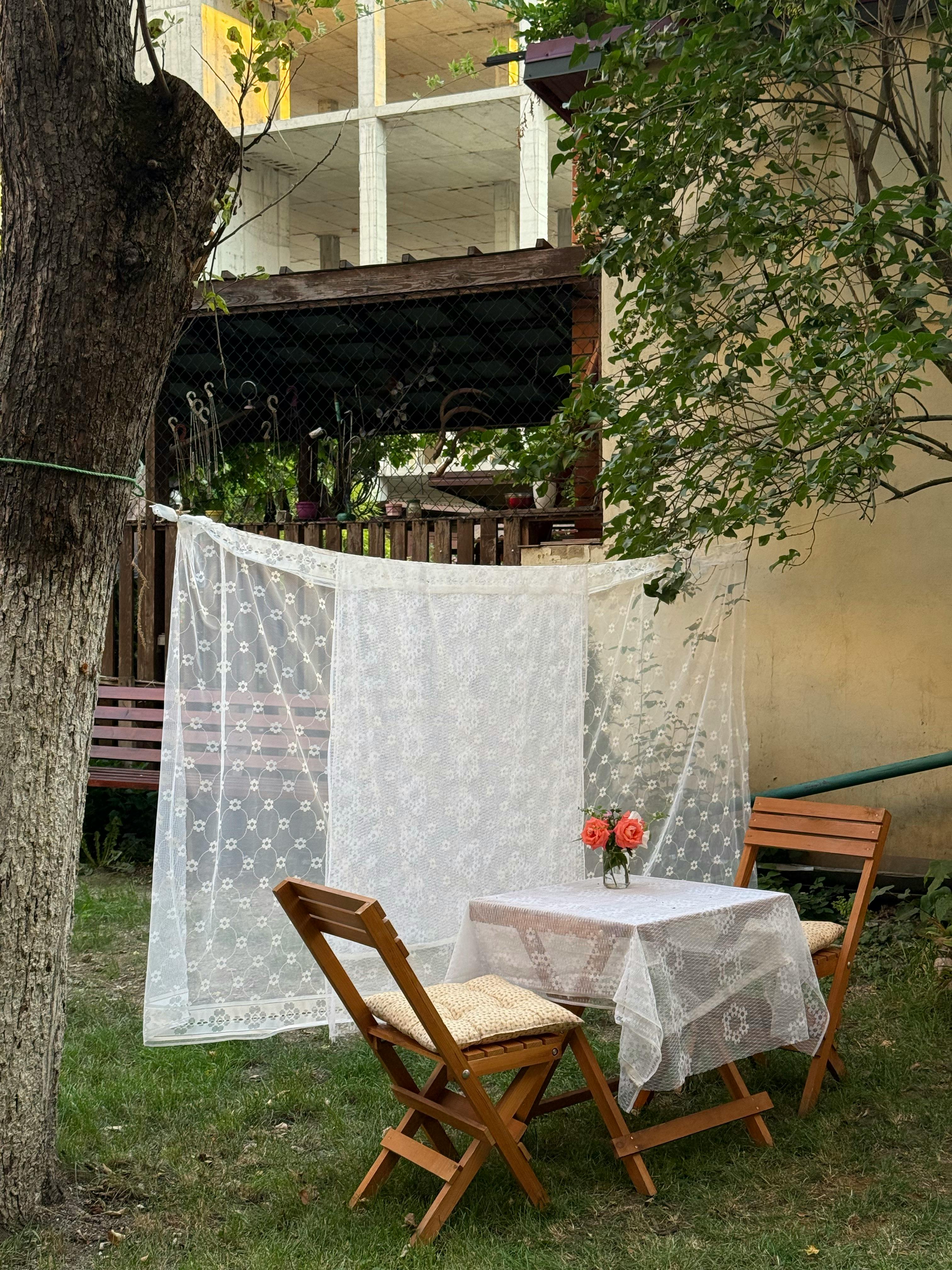 Charming outdoor garden setup with lace-decorated table and chairs. Perfect for a quaint dining experience.