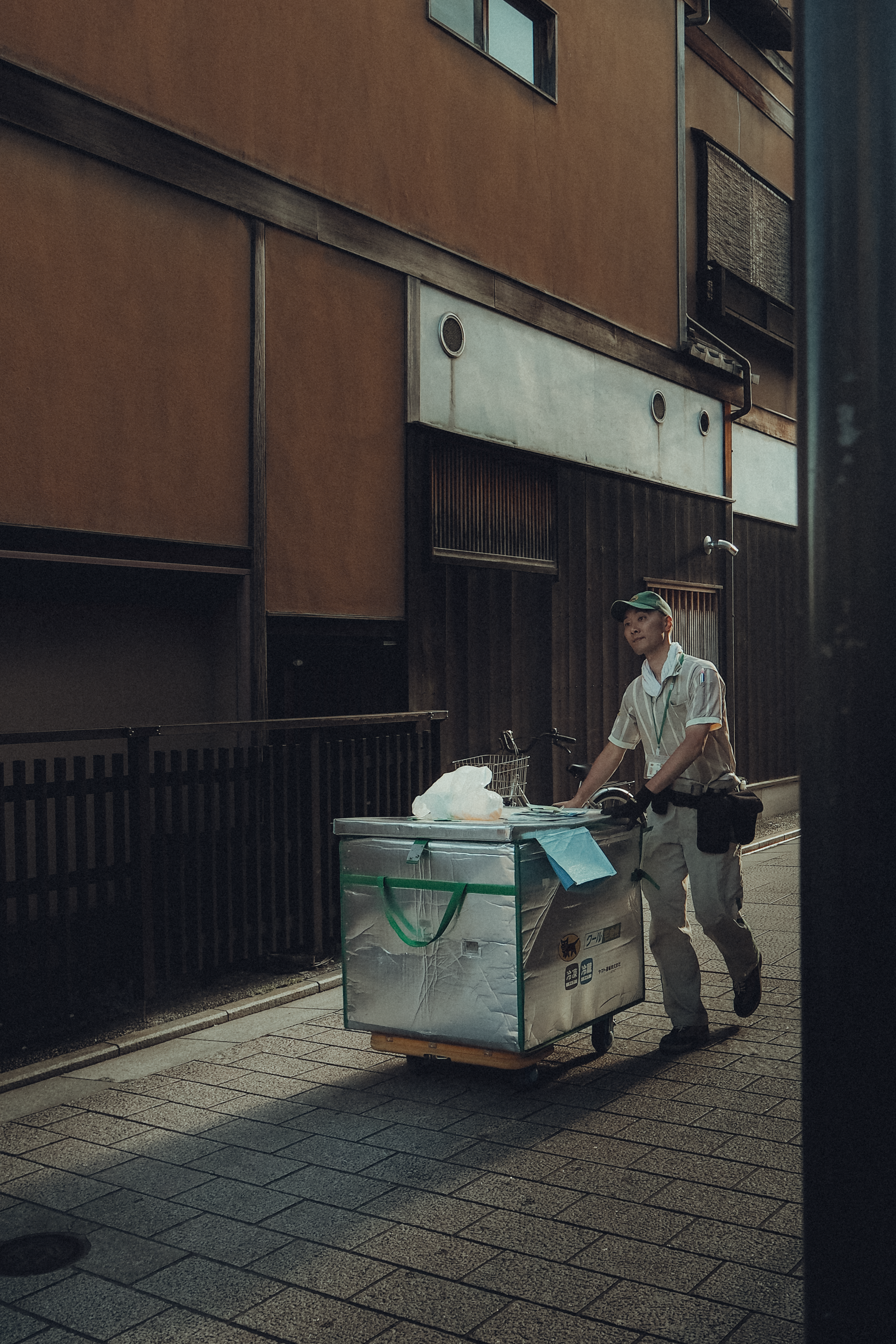 A street vendor pushes cart in a narrow alleyway with traditional architecture.