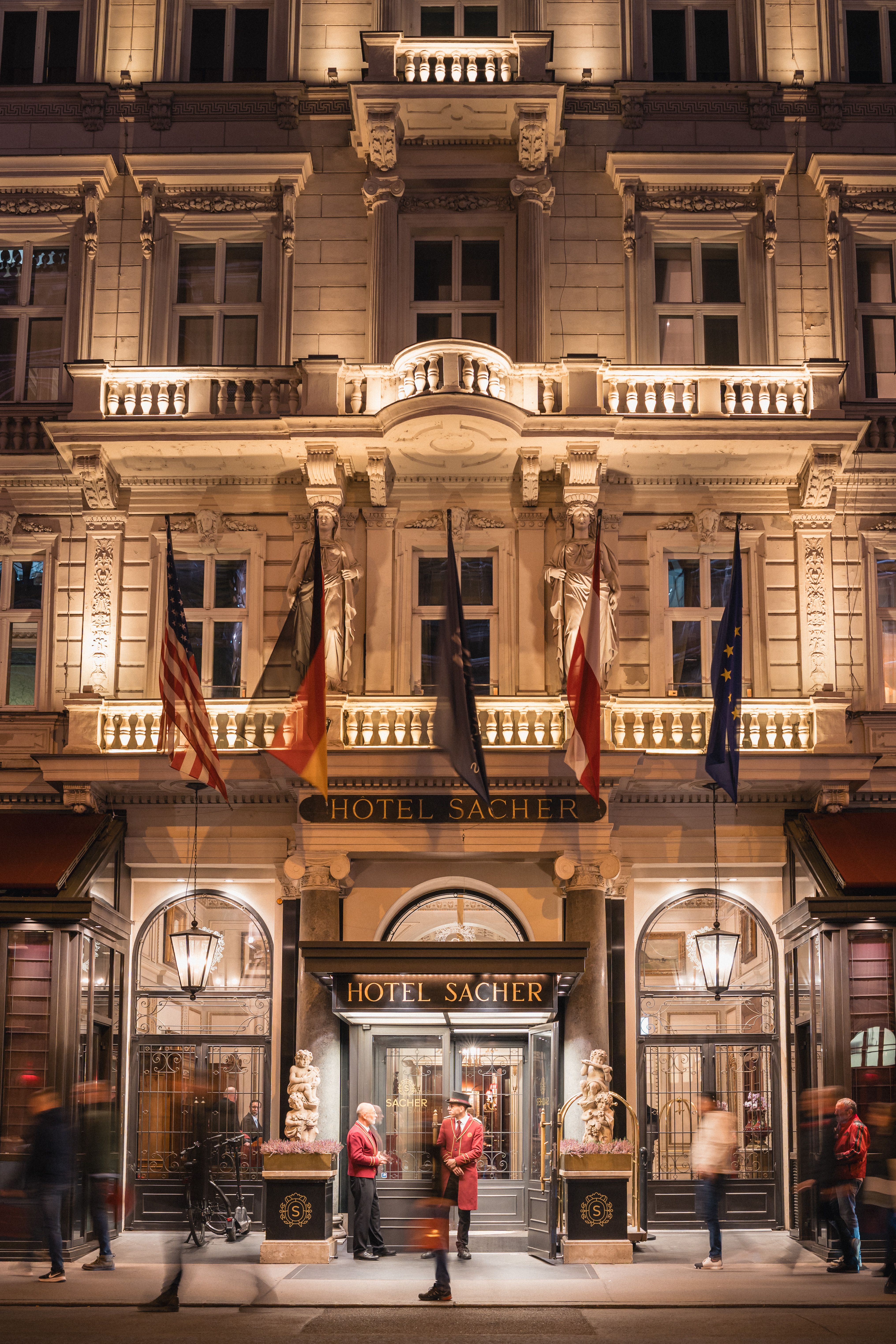 Illuminated Hotel Sacher in Vienna showcasing elegant architectural details at night.