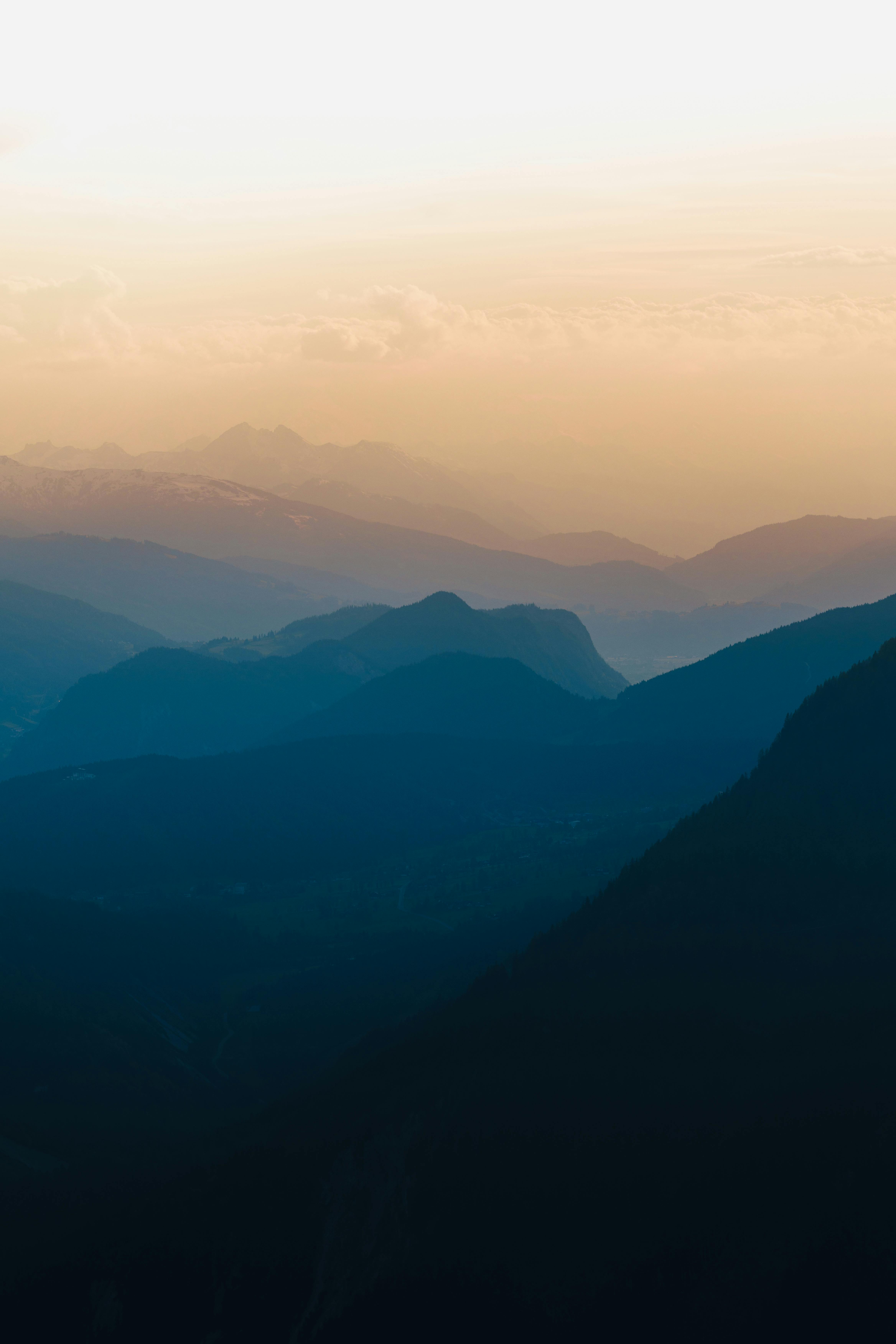 Captivating view of layered blue mountains under a golden sky at sunrise in Austria.