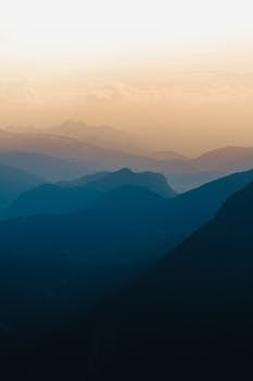 Captivating view of layered blue mountains under a golden sky at sunrise in Austria.