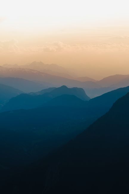 Captivating view of layered blue mountains under a golden sky at sunrise in Austria.