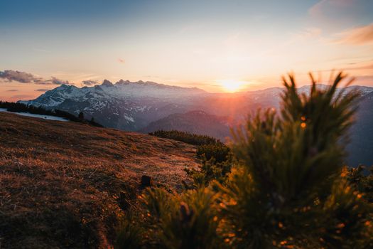 A stunning sunset over the Austrian Alps with snow-covered peaks in a serene landscape.