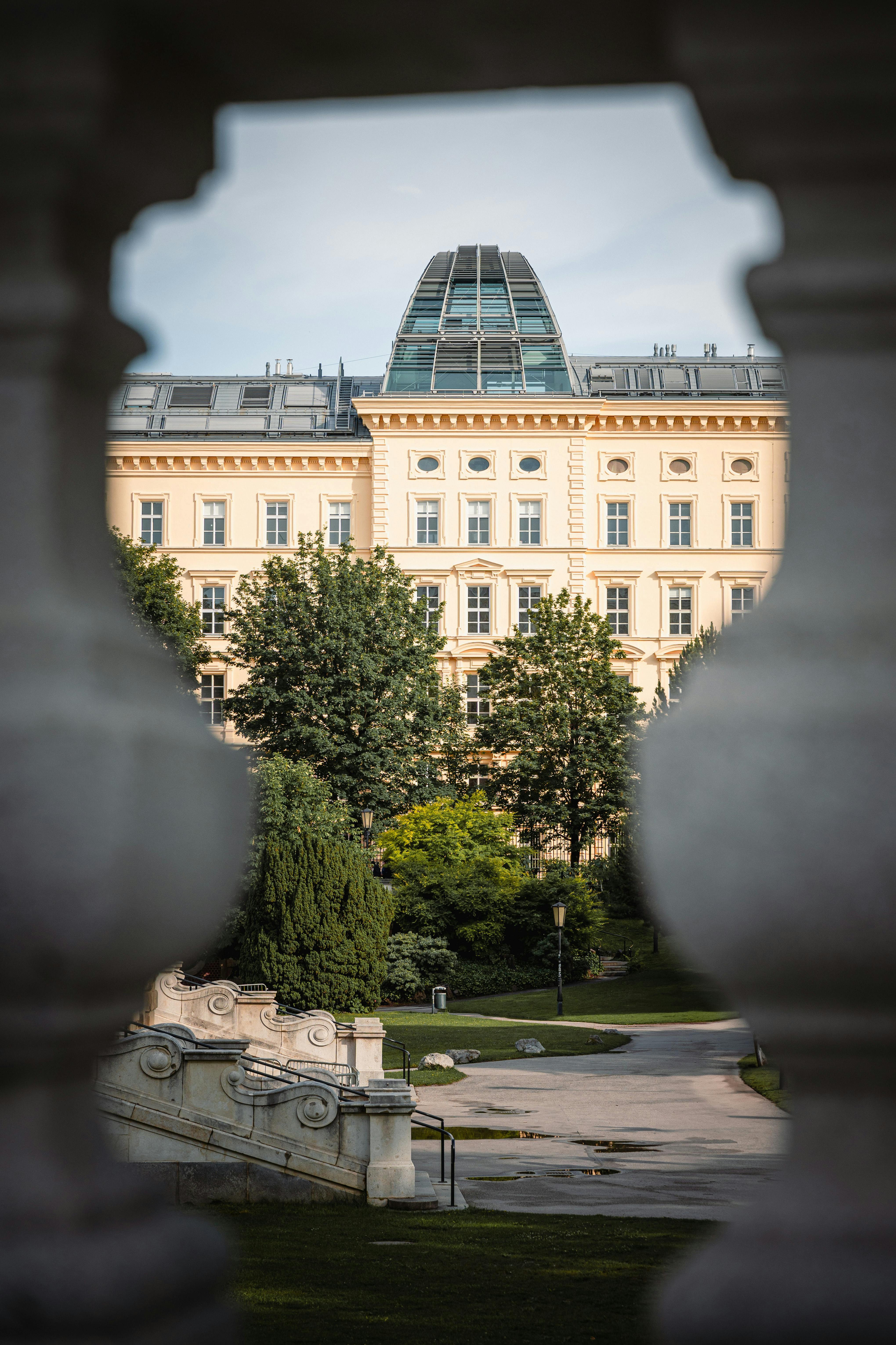 A beautifully framed view of an elegant historic building through ornate stone railings in Vienna.