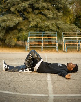 Young adult male lying on a sunny outdoor basketball court, captured on a peaceful day.