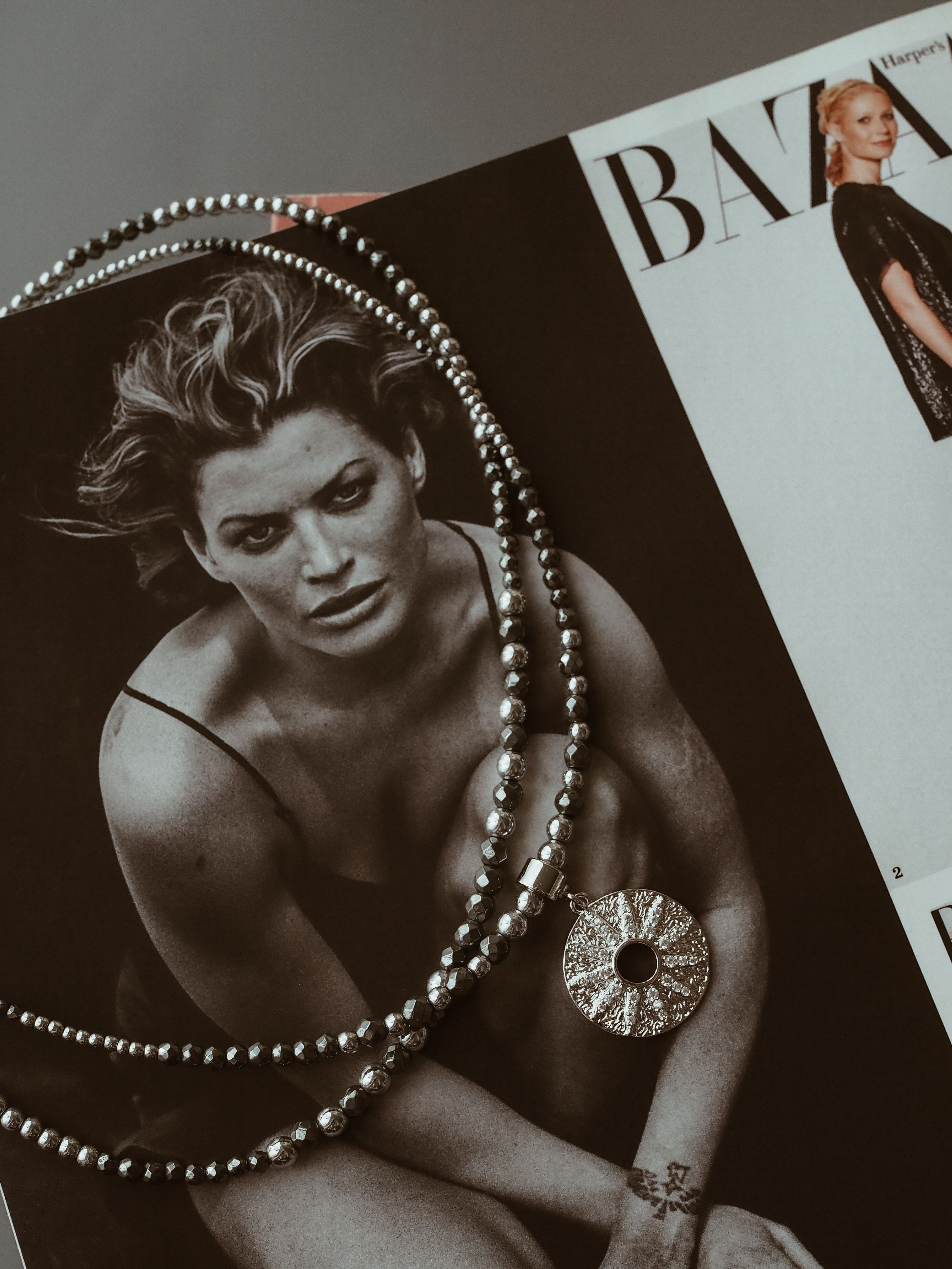 Free Elegant necklace placed on a fashion magazine featuring models. Stock Photo