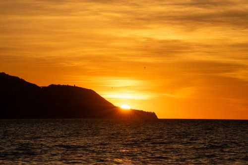 Free Capture of a vibrant sunset over the sea with silhouette of Nerja's coastline. Stock Photo
