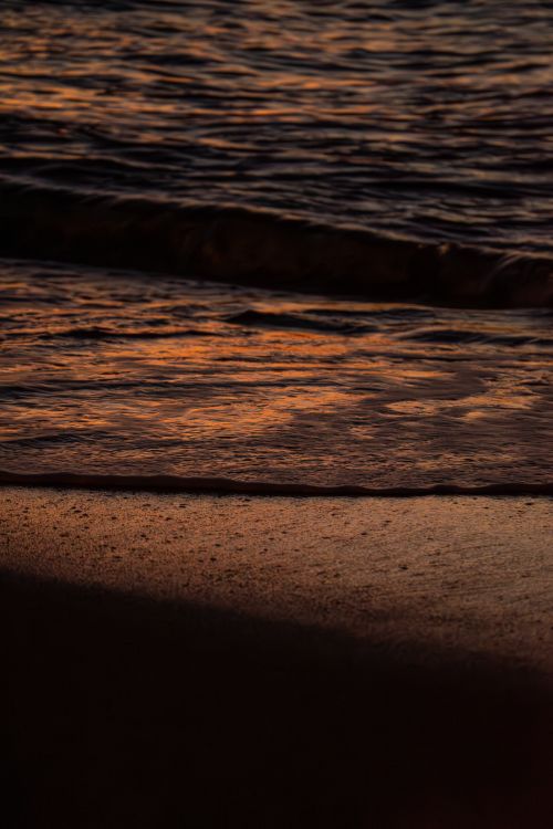 Free Peaceful sunset waves on Nerja Beach with a warm, glowing horizon. Stock Photo