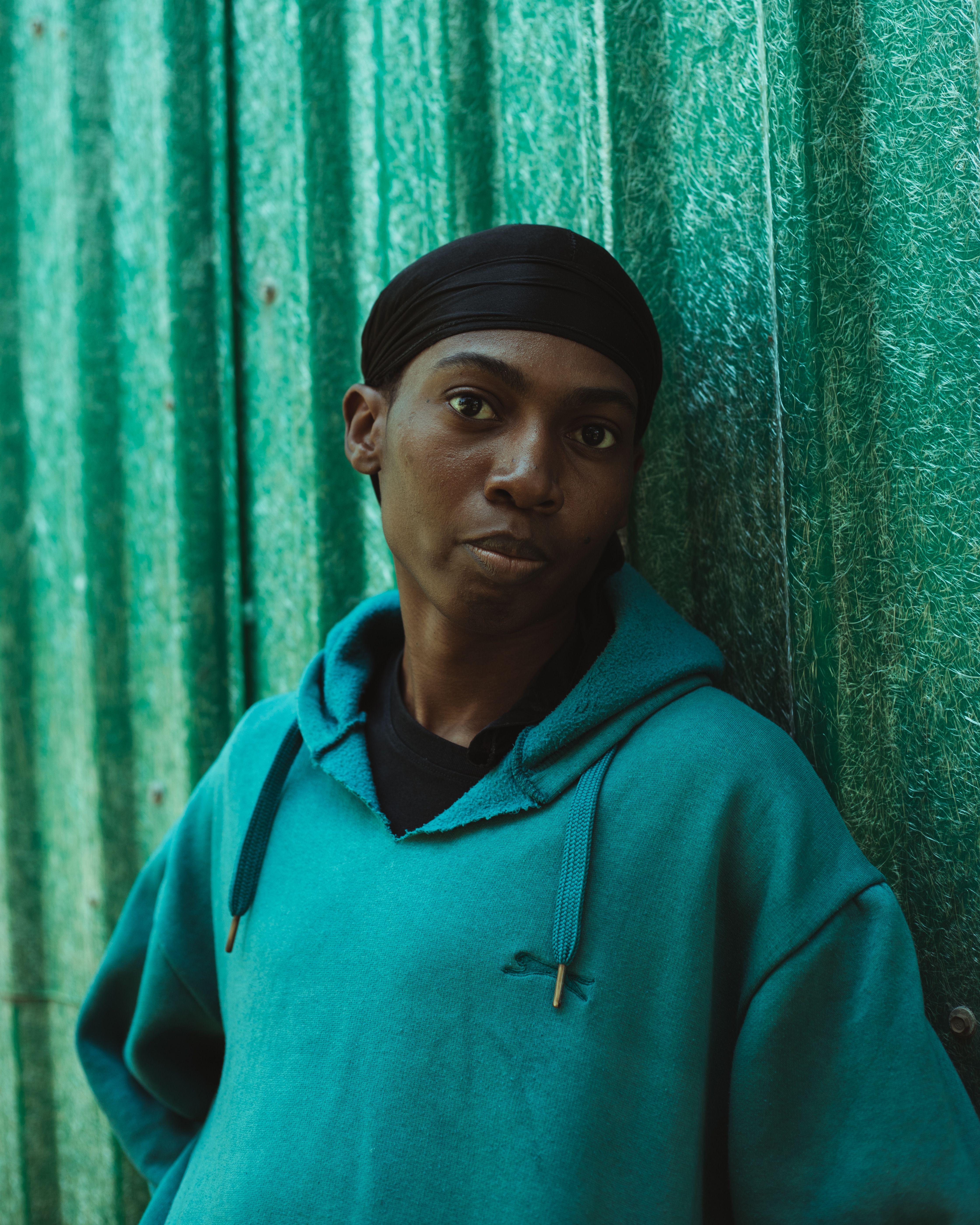 Portrait of Person in Green Hoodie Against Fence · Free Stock Photo