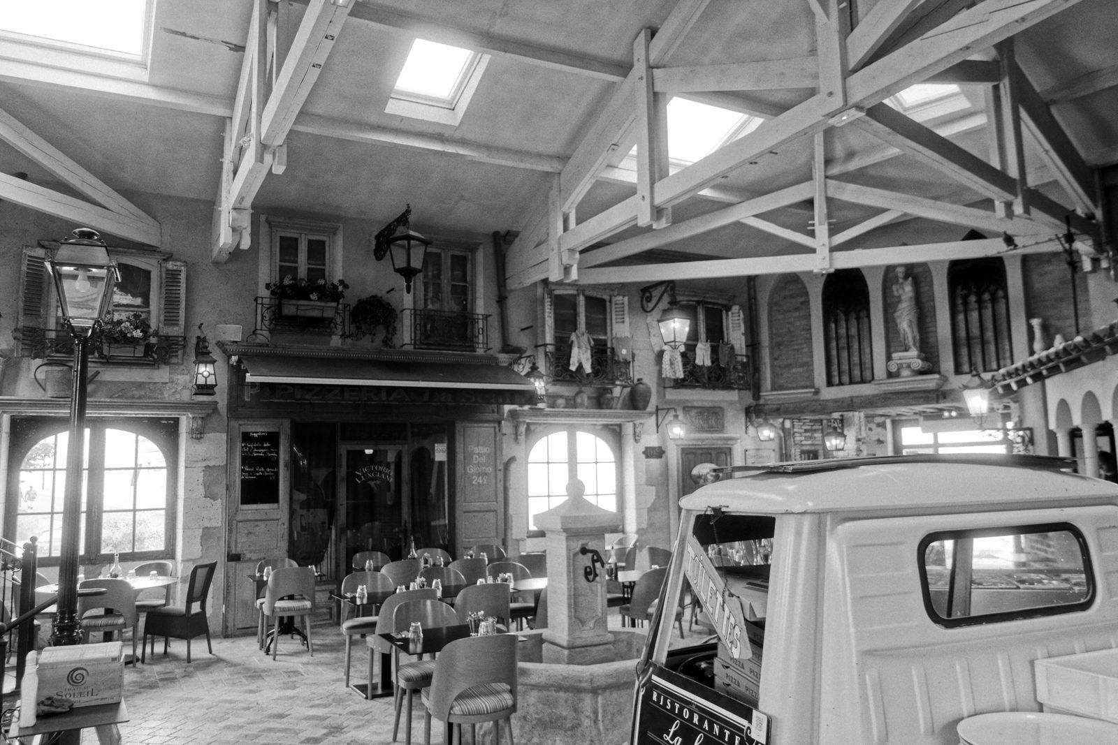 Café sous verrière en noir et blanc avec un triporteur ancien