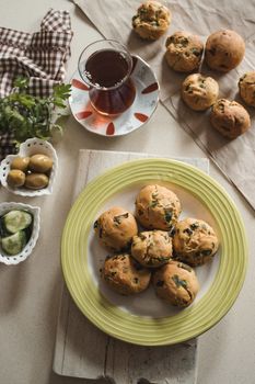 Freshly baked herb bread rolls on a plate with tea, perfect for a cozy breakfast.