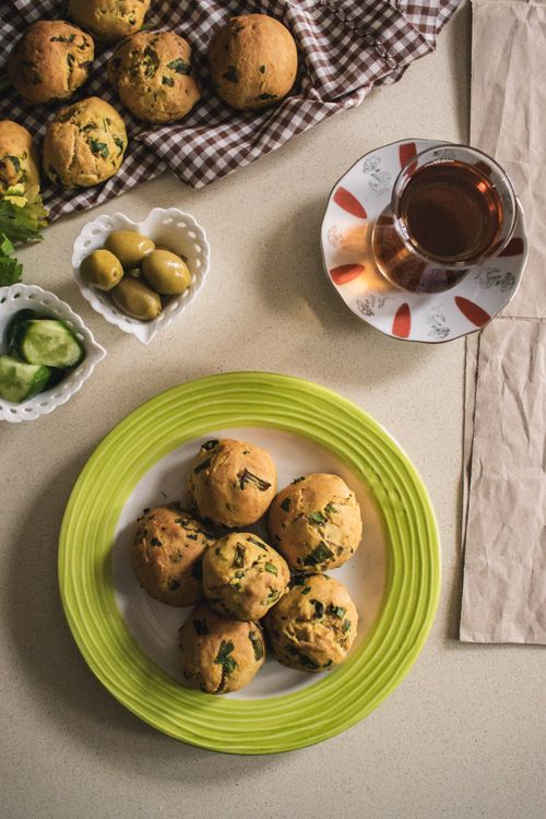 Free A top view of savory muffins on a plate with tea, olives, and cucumbers, creating a cozy homemade meal setting. Stock Photo
