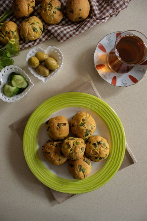 Free Delicious breakfast table with tea, muffins, olives, and cucumbers served on a bright plate. Stock Photo