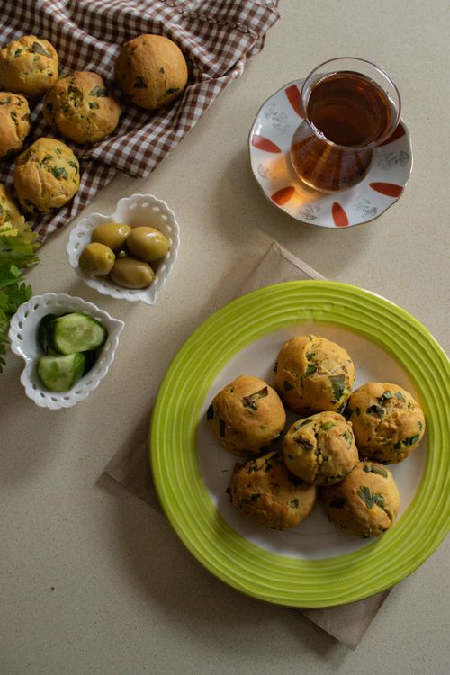 Free A cozy breakfast setup featuring scones with tea, olives, and cucumbers. Stock Photo