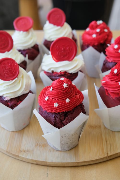 Free A batch of red velvet cupcakes with cream cheese frosting and decorative stars, perfect for celebrations. Stock Photo