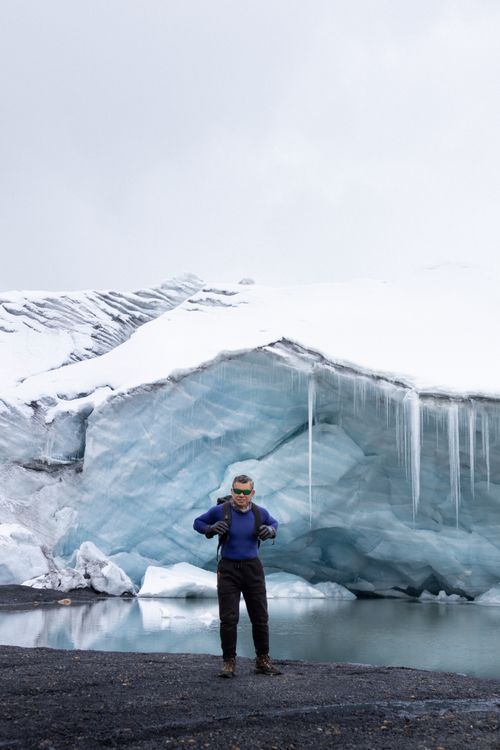 Free Adventurer posing with gear by a stunning icy glacier landscape, symbolizing exploration. Stock Photo