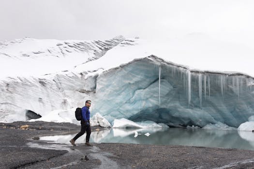 徒步旅行者在冰雪碧绿的冰洞附近探索，捕捉到冬日宁静的景象