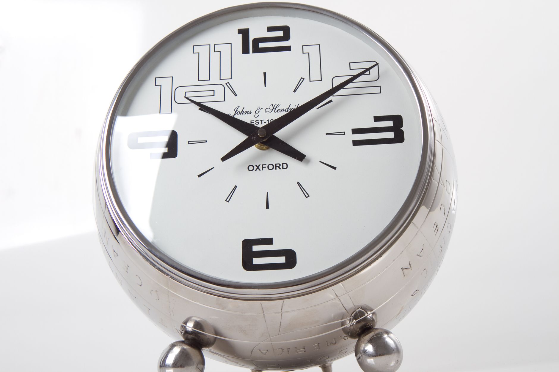Close-up of a modern chrome table clock with bold numerals and clean design.