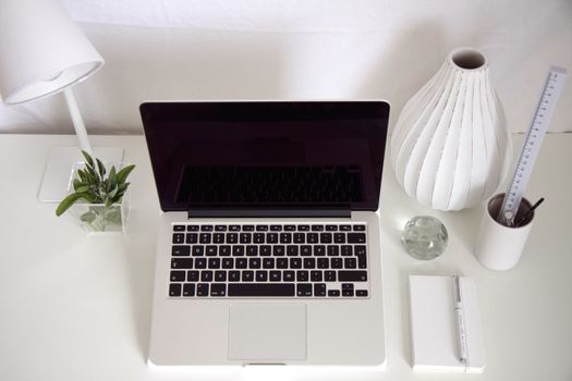 Top-down view of a stylish, minimalist workspace featuring a laptop, lamp, and modern decor.