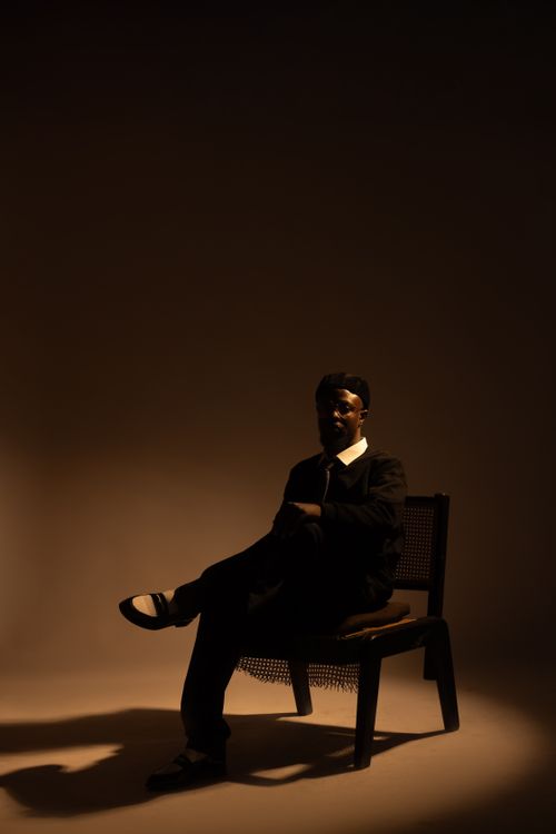Free A man seated in dim lighting creating a moody and dramatic silhouette. Stock Photo