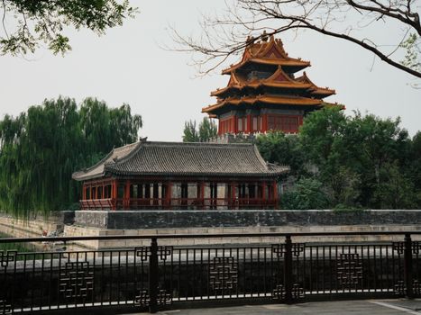 Stunning view of the Forbidden City watchtower with lush greenery, capturing traditional Chinese architecture.