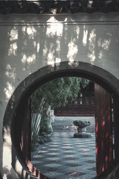 Free Peaceful view of an Asian garden through a traditional circular gate. Stock Photo