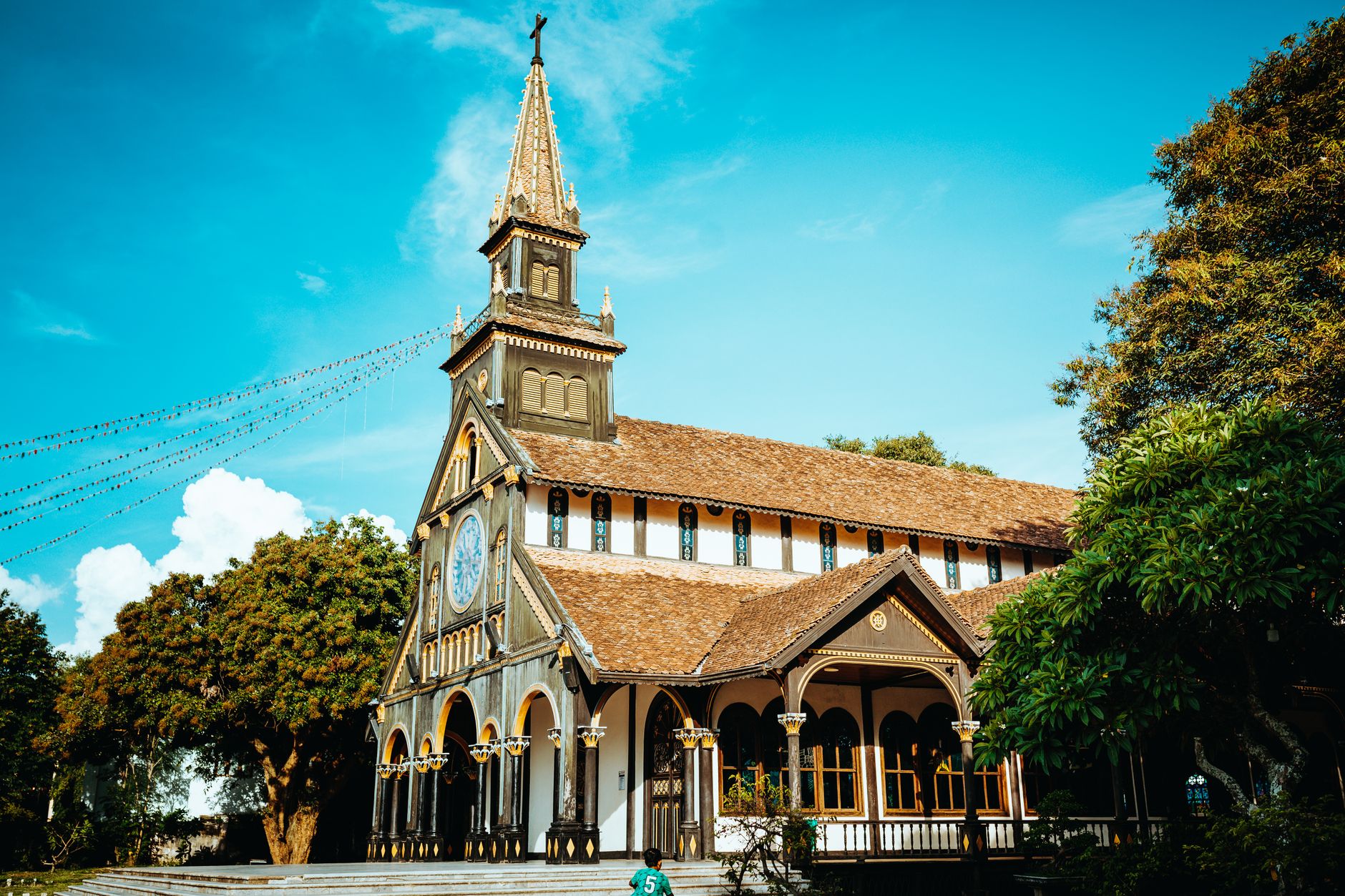 Stunning view of the wooden cathedral in Kon Tum, Vietnam under a bright blue sky.