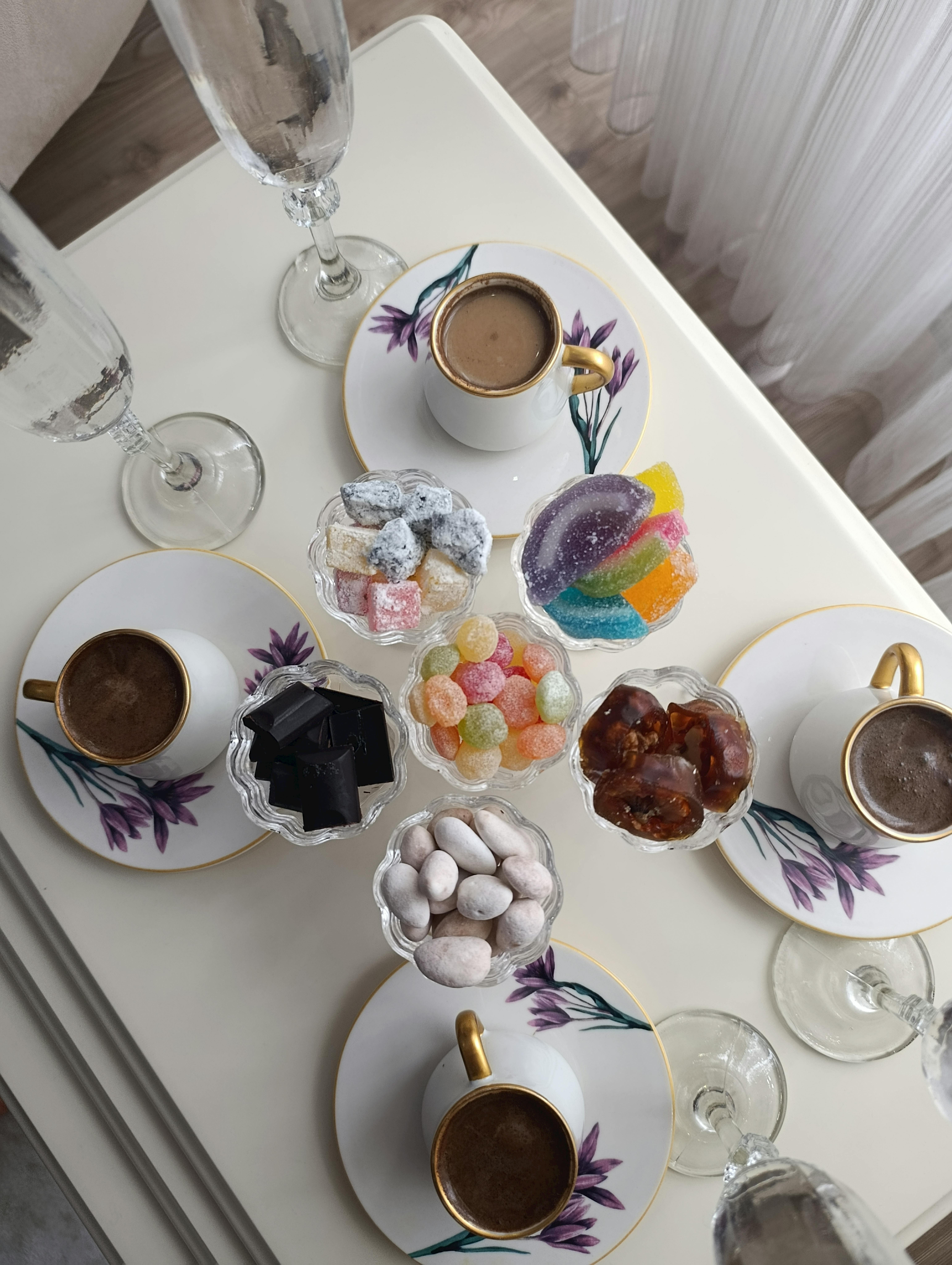 Top view of a stylish coffee table setting with cups, saucers, and assorted sweets.