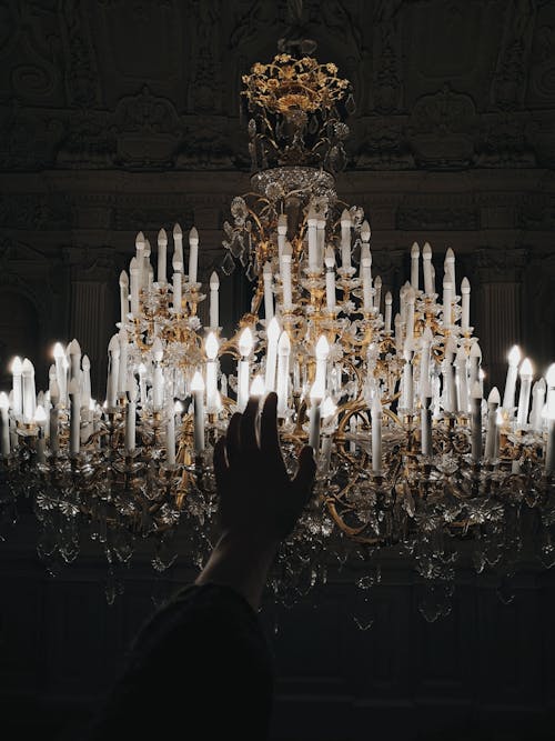 Photo Of Person's Hand Near Chandelier