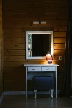 Elegant vanity table with a lamp in a warmly lit wooden interior.