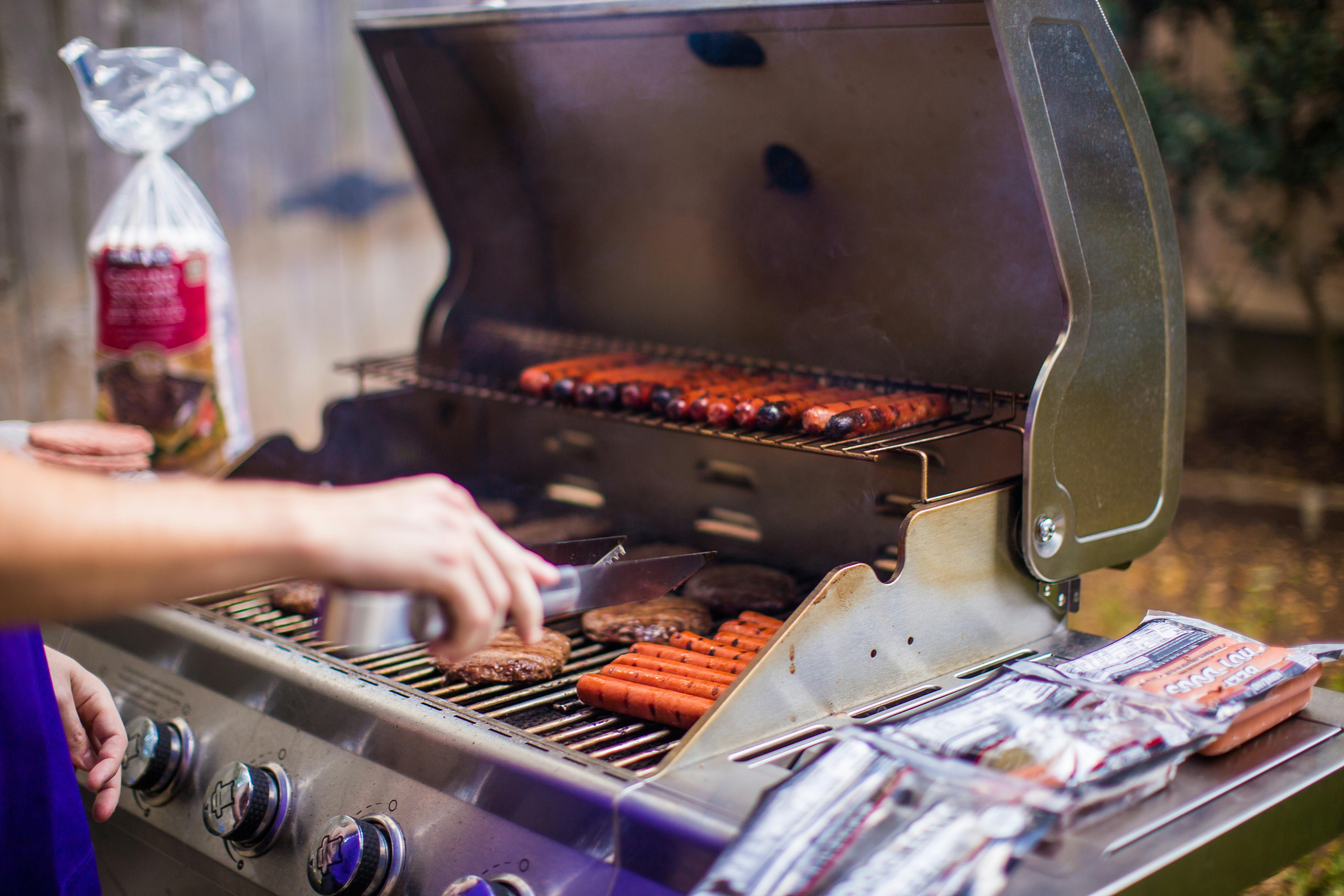 A backyard barbecue grilling sausages & burgers on a sunny day.
