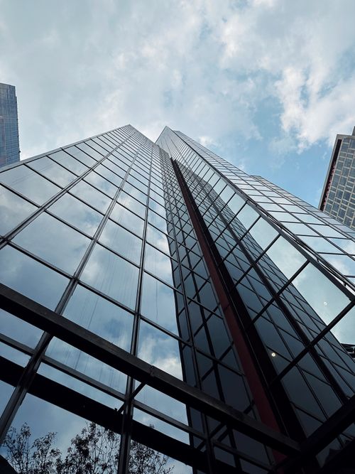 Free Angled view of a glass skyscraper reflecting a cloudy sky, symbolizing urban architecture and modernity. Stock Photo